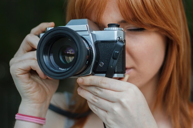 Giovane donna con fotocamera retrò nel parco