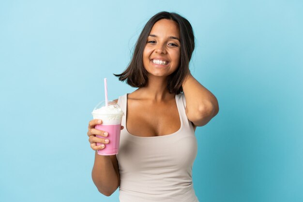 Giovane donna con frappè alla fragola isolato sulla risata blu