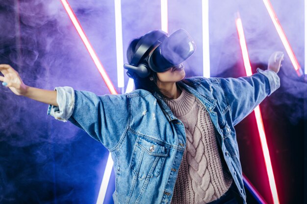 Giovane donna con giacca di jeans blu utilizzando occhiali per realtà virtuale