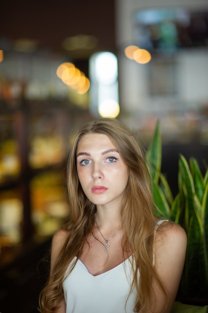 Giovane donna con gli occhi azzurri che si siede sul caffè urbano. donna con acconciatura ondulata marrone. Concetto di stile di vita.