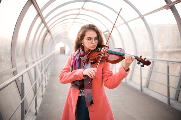 Giovane donna con gli occhiali che suona un violino