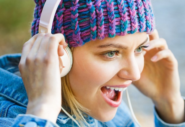 Giovane donna con grandi cuffie Ragazza allegra che si rallegra ascoltando musica in cuffia sorridente
