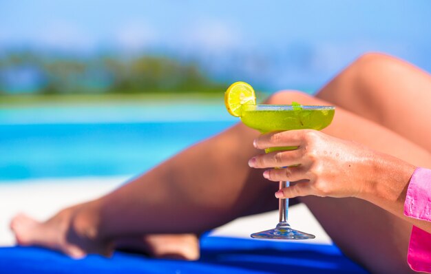 Giovane donna con gustoso cocktail su lettini da spiaggia