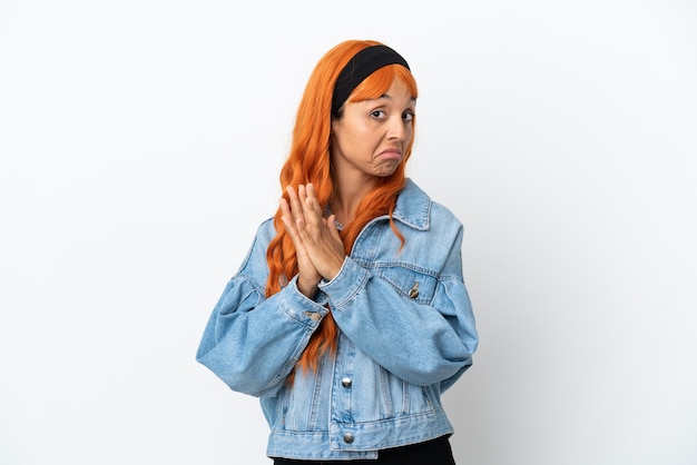 Giovane donna con i capelli arancioni isolata su sfondo bianco che trama qualcosa