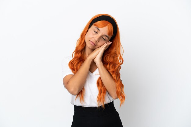Giovane donna con i capelli arancioni isolati su sfondo bianco che fa il gesto del sonno in un'espressione adorabile