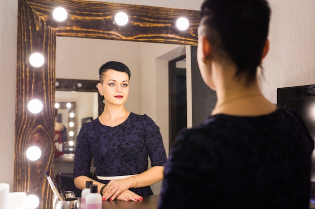 Giovane donna con i capelli corti che si guarda riflesso nello specchio