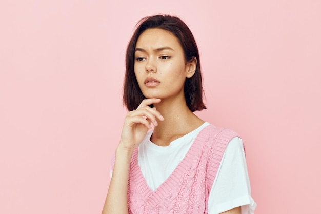 Giovane donna con i capelli corti e un maglione rosa isolato sullo sfondo