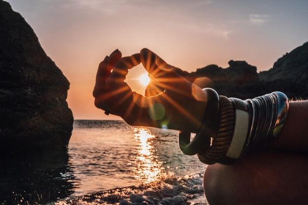 Giovane donna con i capelli lunghi in costume da bagno bianco e bracciali in stile boho che praticano all'aperto sul materassino da yoga in riva al mare su un tramonto Routine di fitness yoga per donne Stile di vita sano armonia e meditazione