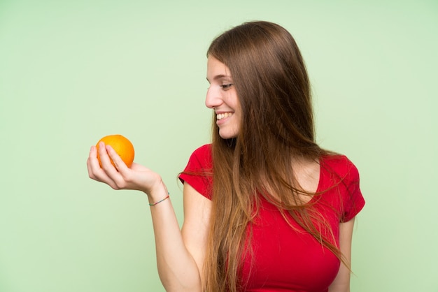 Giovane donna con i capelli lunghi in possesso di un arancio