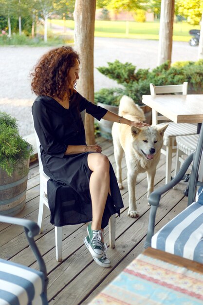 Giovane donna con i capelli ricci che gioca con un cane Akita Inu