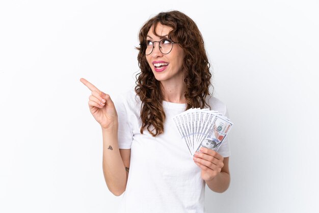 Giovane donna con i capelli ricci che prende un sacco di soldi sfondo isolato su sfondo bianco con l'intenzione di realizzare la soluzione sollevando un dito