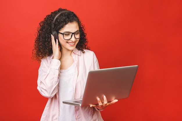 Giovane donna con i capelli ricci del brunet con il computer portatile