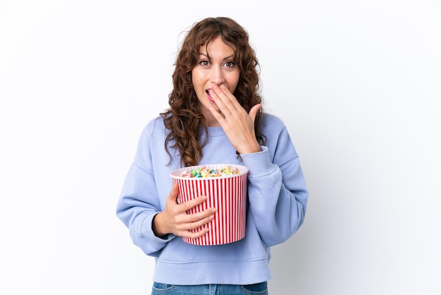 Giovane donna con i capelli ricci isolato su sfondo bianco con in mano un grande secchio di popcorn