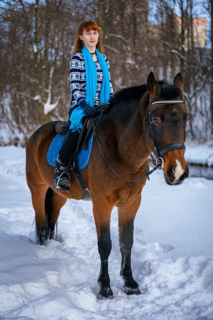 Giovane donna con i capelli rossi su un cavallo in inverno