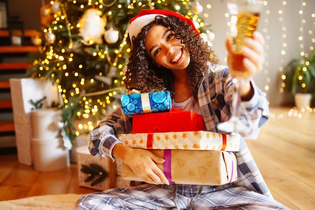 Giovane donna con i regali di Natale a casa vicino all'albero di Natale Vacanze invernali Capodanno