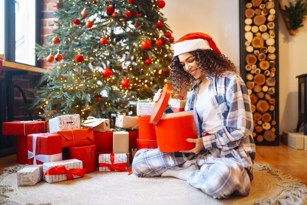 Giovane donna con i regali di Natale a casa vicino all'albero di Natale Vacanze invernali Capodanno