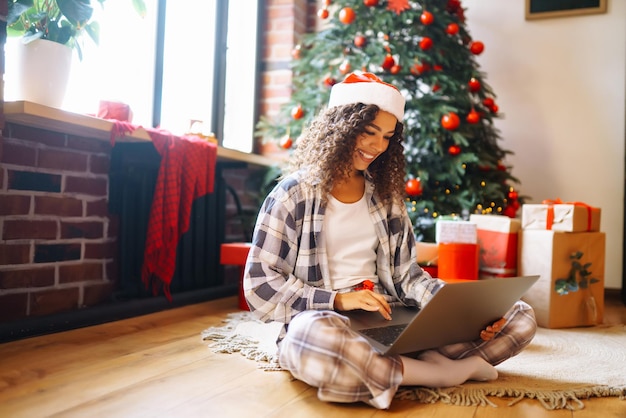 Giovane donna con i regali di Natale a casa vicino all'albero di Natale Vacanze invernali Capodanno