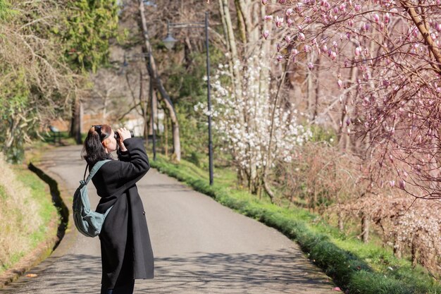 Giovane donna con il binocolo nel parco di primavera