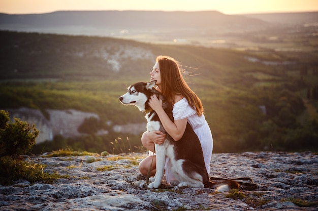 Giovane donna con il cane Husky in una giornata di sole seduti in alta montagna