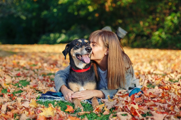 Giovane donna con il cane sdraiato sulle foglie durante l'autunno