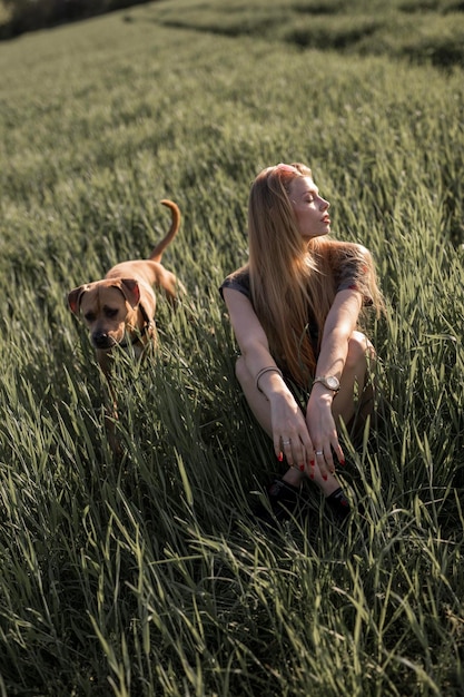 Giovane donna con il cane seduta sul campo erboso