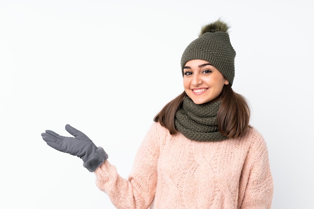 Giovane donna con il cappello di inverno che tiene copyspace immaginario sulla palma