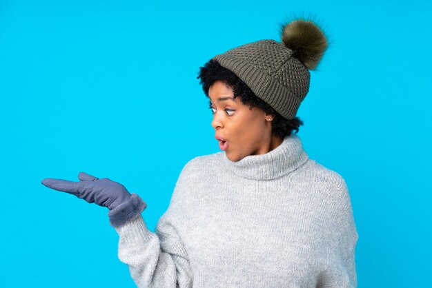 Giovane donna con il cappello di inverno sopra la parete isolata