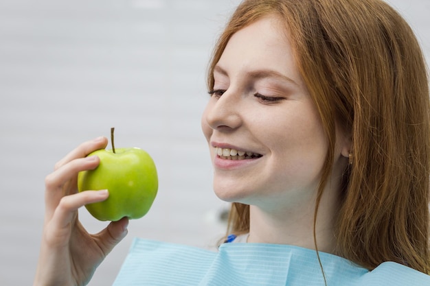 Giovane donna con il dente sano che morde la mela verde