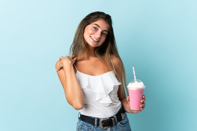 Giovane donna con il frappè alla fragola isolato ridendo