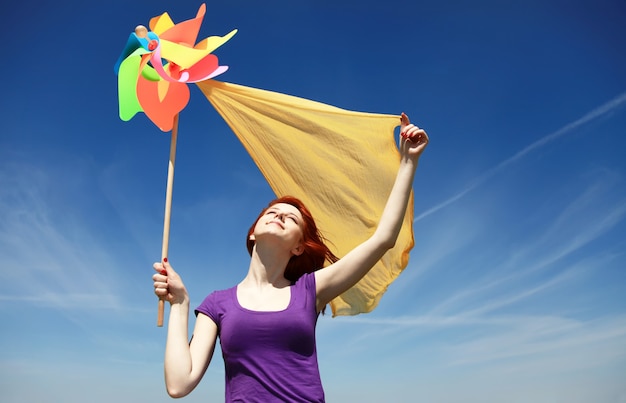 Giovane donna con il giocattolo del pinwheel sulla priorità bassa del cielo