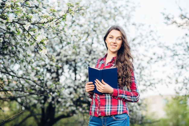 Giovane donna con il libro in un giardino fiorito