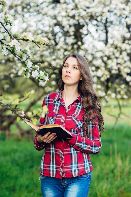 Giovane donna con il libro in un giardino fiorito