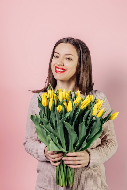 Giovane donna con il mazzo di fiori giallo dei tulipani