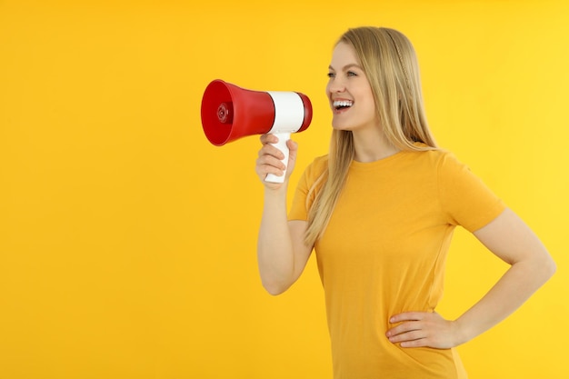 Giovane donna con il megafono su sfondo giallo