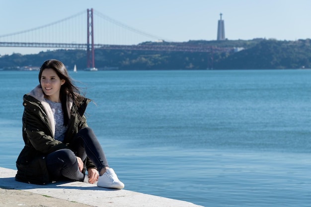 Giovane donna con il ponte del 25 aprile sullo sfondo lisbona portogallo