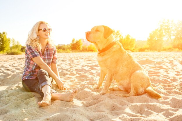 Giovane donna con il suo cane al bagliore del sole della spiaggia
