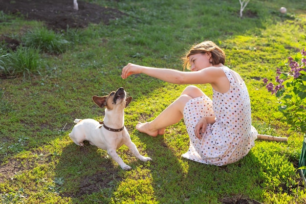 Giovane donna con il suo cane jack russell terrier che gioca sull'erba all'esterno