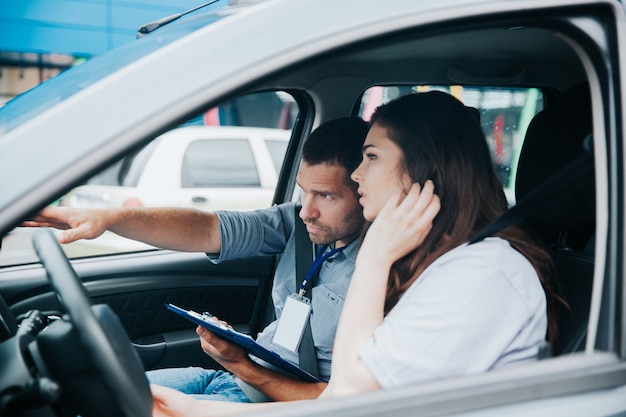 Giovane donna con il suo istruttore di auto in auto