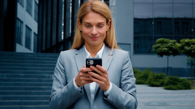 Giovane donna con il telefono in mano digitando il messaggio di posta elettronica aziendale rispondendo imprenditrice sorridente