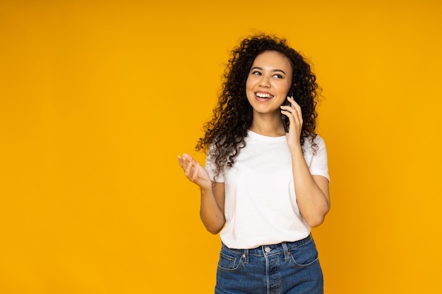 Giovane donna con il telefono su sfondo giallo