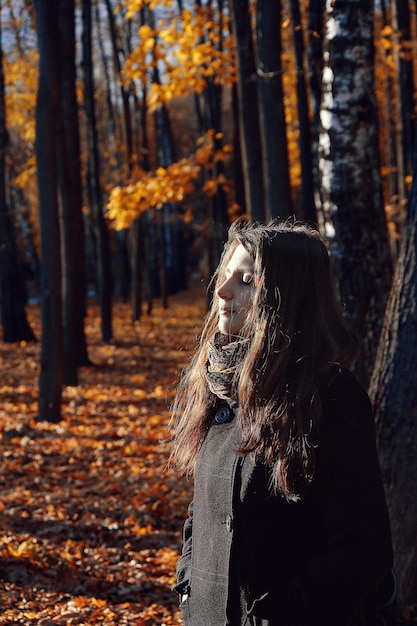 Giovane donna con il tronco di un albero nella foresta durante l'autunno