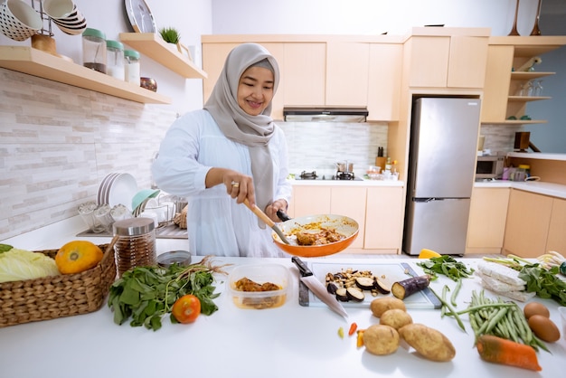 Giovane donna con l'hijab che cucina nella sua casa con cucina moderna per la cena