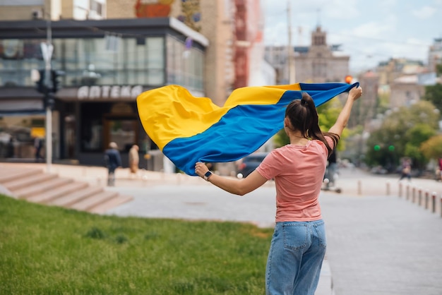 Giovane donna con la bandiera nazionale dell'Ucraina sulla strada