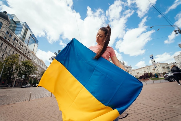 Giovane donna con la bandiera nazionale dell'Ucraina sulla strada