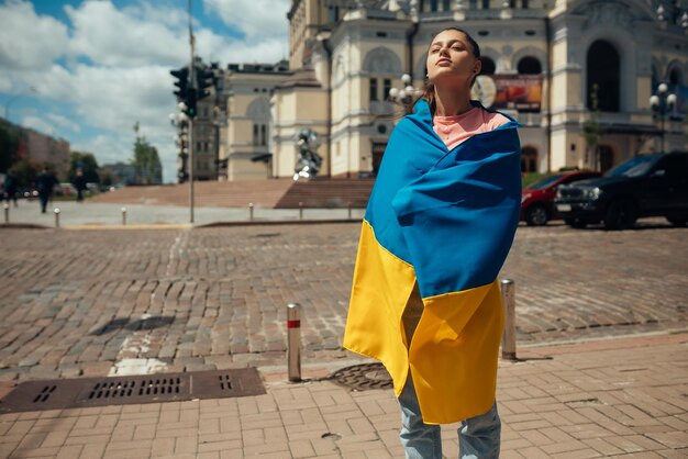 Giovane donna con la bandiera nazionale dell'Ucraina sulla strada