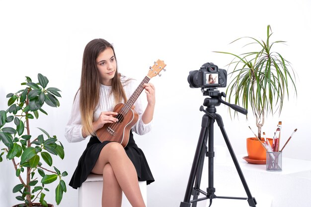 Giovane donna con la chitarra la creazione di contenuti online su sfondo bianco con copia spazio