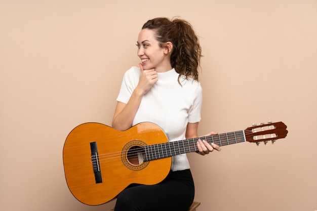 Giovane donna con la chitarra sopra il lato di sguardo isolato