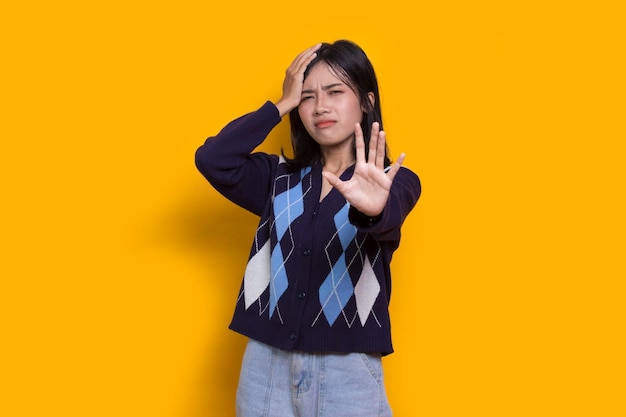 giovane donna con la mano aperta facendo segno di stop gesto di difesa espressione seria su sfondo giallo