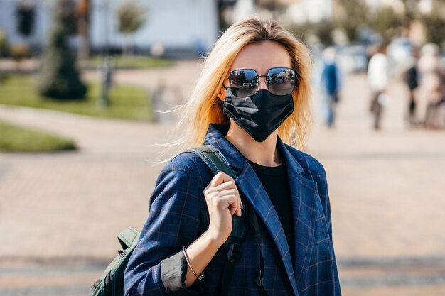 Giovane donna con la maschera che cammina in città