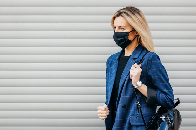 Giovane donna con la maschera che cammina in città